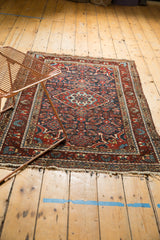 Tattered fringe detail and patterned madder root red and navy blue border of the vintage Dargezine rug.
