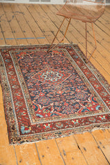 Corner of vintage Persian Dargezine rug with Herati motif, madder red border, tattered fringe.