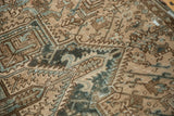 Distressed vintage Heriz rug detail with beige, brown, blue geometric patterns and worn knot heads.