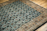 Distressed vintage Oushak carpet segment: faded teal field with black and apricot palmettes, geometric border.