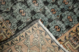 Distressed vintage Oushak pile in faded black, teal, apricot, showing foundation and geometric border.