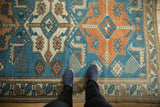 Distressed low pile of a vintage sky blue and tangerine Oushak rug underfoot.