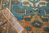 Distressed vintage Oushak rug with geometric blue Akstafa animal and latched diamond motifs.