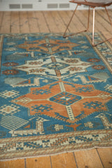 Distressed Oushak rug corner, low pile Akstafa border with sky blue and tangerine geometric motifs.