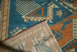 Distressed Oushak rug's folded corner, showing low sky blue pile, hand-knotted back, fringe.