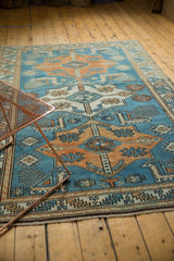Sky blue, tangerine, and ivory serrated leaf border of the vintage Oushak rug with fringe.