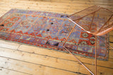 Distressed Oushak runner with faded purple, madder red, and geometric patterns.