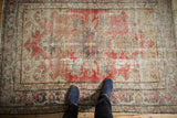 Vintage distressed Oushak rug showing Rococo stylized contours in faded cherry red and sand.