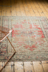 Vintage distressed Oushak rug, worn pile with cherry red, blush, and Rococo motifs.