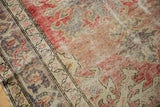 Distressed Oushak rug detail, worn pile with faded red, beige, and oxidized silver patterns.