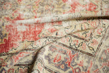 Curvilinear motifs on distressed Oushak rug in faded cherry, sand, and time-softened grey tones.