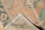 Distressed Oushak runner corner, revealing worn apricot pile, faint foundation, and hand-knotted reverse.