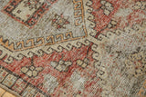 Muted blush, pale red, and silver tones on distressed Oushak rug with even wear.