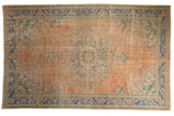 Distressed Oushak carpet, peach field, faded starburst floral medallion, blue borders. 6'5