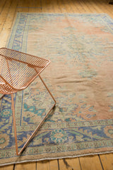 Distressed vintage Oushak carpet with faded rose, peach, blue, green floral motifs.