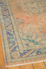Distressed vintage Oushak rug corner with worn peach field, faint foundation, and royal blue border.