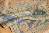 Distressed hand-knotted vintage Oushak detail: faded peach, blue, green, faint foundation.