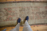Distressed texture of a vintage Oushak runner with repeating medallions and dusty rose tones.