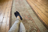 Faded dusty rose and antique ivory medallion patterns on a distressed Oushak runner.