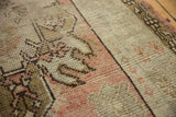 Distressed Oushak runner's hand-knotted texture, revealing worn pile, dusty rose, and brown motifs.