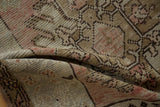 Folded vintage distressed Oushak runner showcasing worn texture and dusty rose patterns.