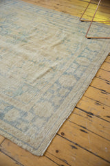 Distressed Oushak carpet showing worn pile, exposed foundation, and faded blue, ivory patterns.