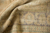 Close-up of the distressed Oushak pile with muted ivory, sand, and pale apricot tones.