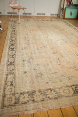 Distressed Oushak border featuring faded lotus palmettes and coffee chocolate hues, with short fringe.