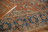 Distressed Turkish Oushak rug section with faded rust and blue scrolling vinery and border.