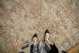 Distressed vintage Oushak carpet displaying pale blush rose and ivory patterns with even wear.