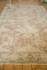 Distressed Oushak rug border with pale blush rose, ivory, and charcoal patterns.