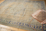 Distressed Oushak rug corner with worn texture, abrash, and faded dusty royal blue motifs.