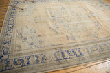 Corner detail of distressed Oushak carpet with worn dusty royal blue border patterns.