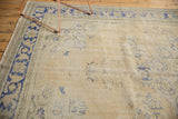 Distressed Oushak rug texture, faded dusty blue floral motifs on pale sand field.