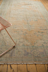 Distressed Oushak rug pile revealing faded apricot, ivory, and denim blue tones.