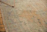 Distressed Oushak carpet pile showing mostly even wear, faded apricot, blue, green, and selvage.