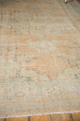 Textured surface of a distressed Oushak rug showing worn pile and pale apricot tones.