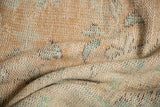 Textured pile of distressed Oushak rug with soft apricot, ivory, and mint green.