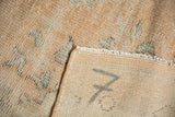 Reverse of vintage distressed Oushak rug, showing processing numbers and exposed foundation.