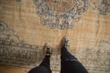 Distressed Oushak rug's worn beige pile and time-softened blue medallion.