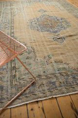 Distressed Oushak rug corner showcasing muted blue, mint green, and charcoal border details.