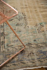 Distressed vintage Oushak carpet close-up, showing muted beige, mint, and dusty blue tones.