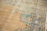 Distressed Oushak rug showing mostly even wear on beige pile, small areas of foundation, and faded blue and green patterns.