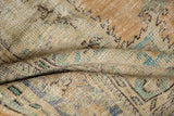Distressed Oushak carpet with worn pile texture and muted beige, mint, and dusty blue patterns.