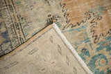 Folded corner reveals woven foundation and distressed beige, green, blue Oushak pile.