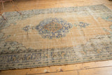 Distressed Oushak rug's side edge with blue-green border patterns and visible pile wear.