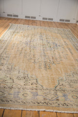 Distressed Oushak carpet's textured pile, showing faded beige and pale blue floral patterns.