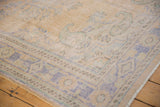 Distressed Oushak rug corner, showing faded blue, sand, mint border pattern and wear.
