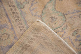 Distressed Oushak rug corner, showcasing worn beige pile texture, exposed foundation, and intact selvage.