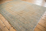 Distressed vintage Oushak rug corner displaying worn beige field, faded blue and mint green border.